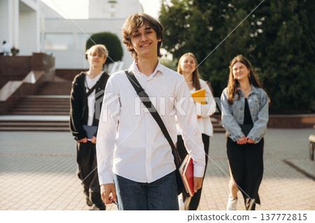 White shirt, positive facial expression. Group of students are near university together White shirt, positive facial expression. Group of students are near university together 137772815
