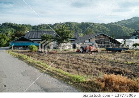 A summer scene in a mountain village with farm work areas and tractors lined up. A summer scene in a mountain village with farm work areas and tractors lined up. 137773009