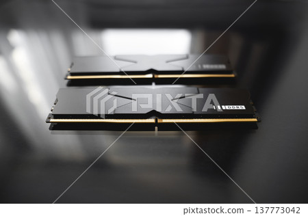 Black DDR5 RAM memory modules placed on a dark, glossy surface. RAM shortages on the market, rising prices, and increased demand driven by the growing need for AI training. Black DDR5 RAM memory modules placed on a dark, glossy surface. RAM shortages on the market, rising prices, and increased demand driven by the growing need for AI training. 137773042