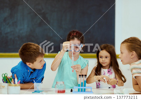Children conducting a science experiment together in a classroom with test tubes and pipette Children conducting a science experiment together in a classroom with test tubes and pipette 137773211