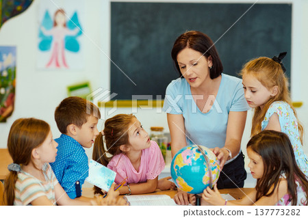 Teacher shows globe to a group of elementary students in a classroom geography lesson 137773282