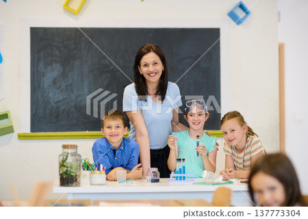 Elementary teacher guiding children in a hands-on science experiment in a bright classroom 137773304