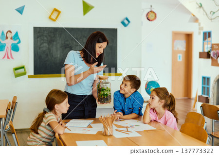 Teacher showing a terrarium to engaged elementary students during a hands-on science lesson in classroom Teacher showing a terrarium to engaged elementary students during a hands-on science lesson in classroom 137773322