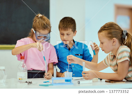 Children doing a hands-on science experiment at school with test tubes and safety goggles Children doing a hands-on science experiment at school with test tubes and safety goggles 137773352