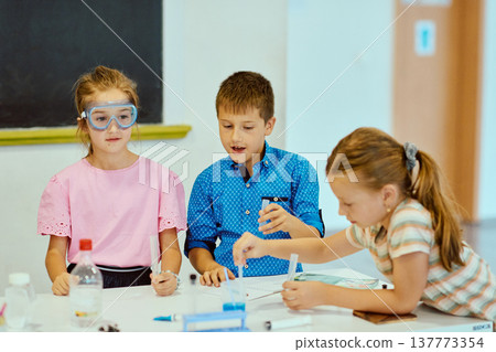Three children doing a science experiment at school table, learning and collaborating in a classroom 137773354