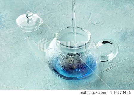 Blue tea, an infusion of butterfly pea flowers, hot water being poured Blue tea, an infusion of butterfly pea flowers, hot water being poured 137773406