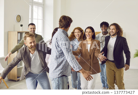 Group of a happy smiling business people having fun greeting coworker in office. Group of a happy smiling business people having fun greeting coworker in office. 137773427