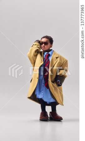 Little boy wearing oversized coat tie and sunglasses posing confidently in studio. Little boy wearing oversized coat tie and sunglasses posing confidently in studio. 137773965