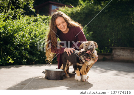 Near a water or food dish. Woman is with cute dogs outdoors Near a water or food dish. Woman is with cute dogs outdoors 137774116