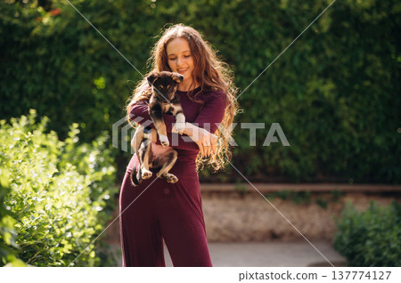 Bright sunlight, animal is in hands. Woman is with cute dog outdoors Bright sunlight, animal is in hands. Woman is with cute dog outdoors 137774127