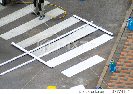 Road Worker Painting Pedestrian Crossing. Applying markings. Paint white color line. Highway crosswalk mark working Road Worker Painting Pedestrian Crossing. Applying markings. Paint white color line. Highway crosswalk mark working 137774165