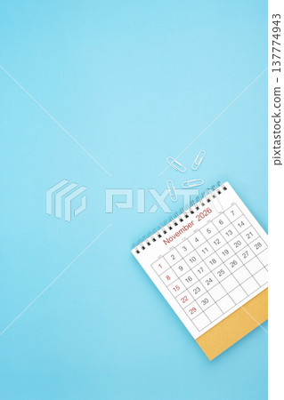 Desk calendar for November 2026 and white paper clip on a light blue background. Desk calendar for November 2026 and white paper clip on a light blue background. 137774943