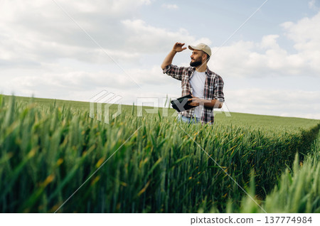 Quality control, with digital tablet. Man farmer is on the agricultural field Quality control, with digital tablet. Man farmer is on the agricultural field 137774984