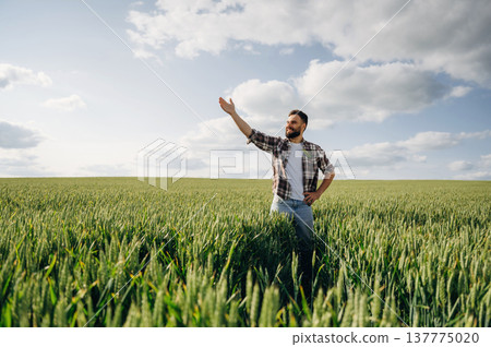 Showing the place by hand. Man farmer is on the agricultural field Showing the place by hand. Man farmer is on the agricultural field 137775020