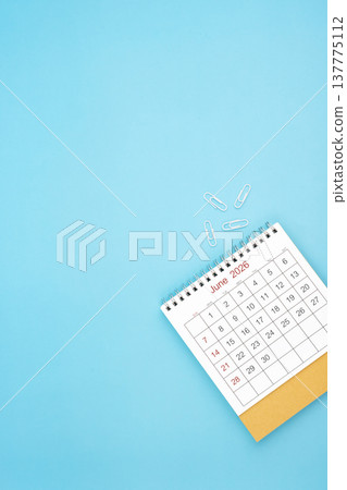 Desk calendar for June 2026 and white paper clip on a light blue background. 137775112