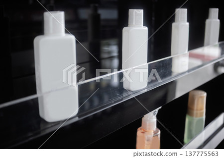 Close-up of small white plastic bottles on a black shelf with a clear acrylic rail. Ideal for travel-sized toiletries, cosmetic packaging, and hotel amenities mockup Close-up of small white plastic bottles on a black shelf with a clear acrylic rail. Ideal for travel-sized toiletries, cosmetic packaging, and hotel amenities mockup 137775563