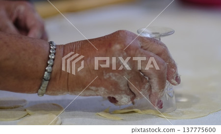 Close-up of hands cutting round dough pieces with a glass during pastry preparation. The footage captures a traditional baking step, useful for homemade recipe videos, cooking lessons, or kitchen Close-up of hands cutting round dough pieces with a glass during pastry preparation. The footage captures a traditional baking step, useful for homemade recipe videos, cooking lessons, or kitchen 137775600