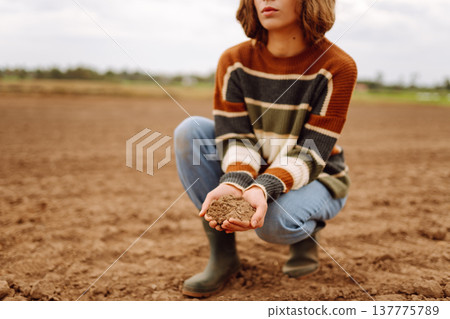 Close up of the female hands touching dry ground in an agricultural field while analyzing soil Close up of the female hands touching dry ground in an agricultural field while analyzing soil 137775789