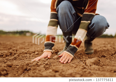 Close up of the female hands touching dry ground in an agricultural field while analyzing soil Close up of the female hands touching dry ground in an agricultural field while analyzing soil 137775811