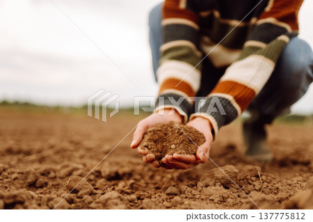 Close up of the female hands touching dry ground in an agricultural field while analyzing soil 137775812