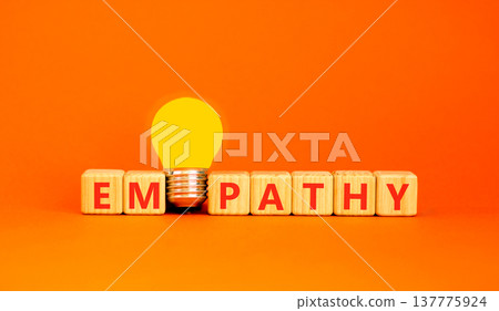 Empathy symbol. The concept word Empathy on wooden cubes. Beautiful white table. Beautiful orange background. Beautiful yellow light bulb. Copy space. Business, psychological and empathy concept. 137775924