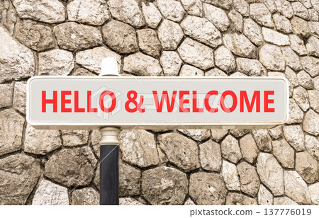 Hello and welcome symbol. Concept words Hello and welcome on beautiful big white road sign. Beautiful grey stone wall background. Business hello and welcome concept. Copy space. Hello and welcome symbol. Concept words Hello and welcome on beautiful big white road sign. Beautiful grey stone wall background. Business hello and welcome concept. Copy space. 137776019