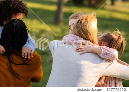 Children embracing adults in a park, sharing a loving moment together Children embracing adults in a park, sharing a loving moment together 137776250