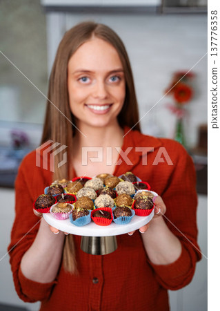 Young woman holding homemade healthy sweet dessert truffles Young woman holding homemade healthy sweet dessert truffles 137776358