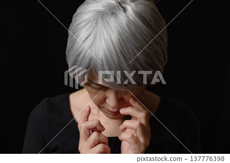 A senior woman with white hair, looking down and frowning. A senior woman with white hair, looking down and frowning. 137776398