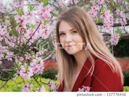 Young woman poses beside blooming cherry blossom trees in a vibrant garden during springtime Young woman poses beside blooming cherry blossom trees in a vibrant garden during springtime 137776430