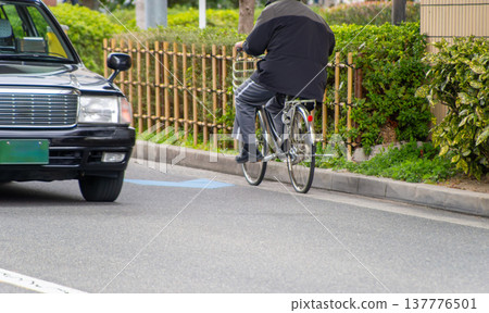 一輛汽車從一輛逆行的自行車旁經過。 137776501