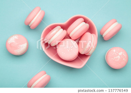 Pink macaroons in heart shaped bowl on blue background Pink macaroons in heart shaped bowl on blue background 137776549