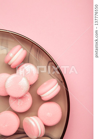 Pink macaroons in white plate on pink background. Vertical photo 137776550