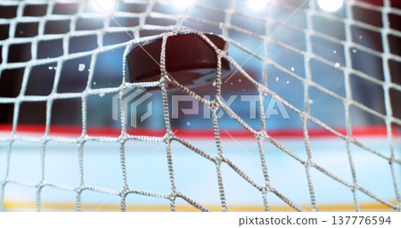 Action sports photo of a hockey puck flying into the goal net during a scoring shot, with ice particles in the air, capturing speed and intensity. Action sports photo of a hockey puck flying into the goal net during a scoring shot, with ice particles in the air, capturing speed and intensity. 137776594