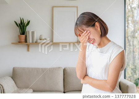 Woman covering her face in living room 137777028