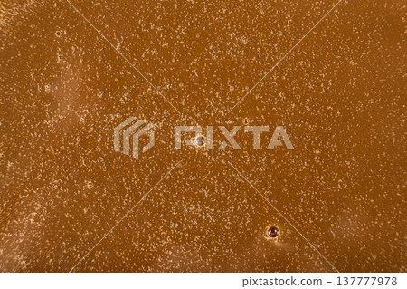 Background of homemade liquid caramel sauce with bubbles. Background of homemade liquid caramel sauce with bubbles. 137777978