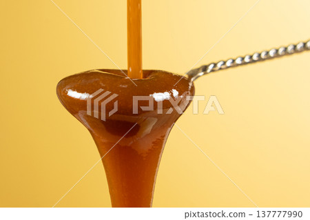 Sweet caramel sauce dripping from spoon, liquid caramel close-up. Sweet caramel sauce dripping from spoon, liquid caramel close-up. 137777990