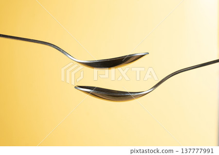 Two empty spoons on yellow background for design. Two empty spoons on yellow background for design. 137777991
