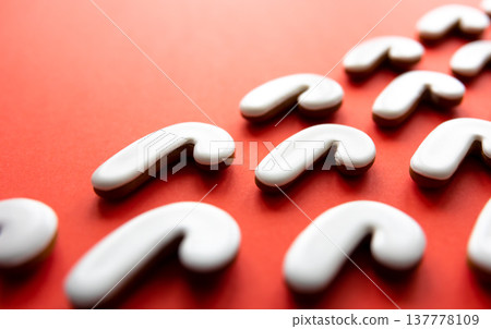 A lot of gingerbread candy cane shaped cookies on a red background. A lot of gingerbread candy cane shaped cookies on a red background. 137778109
