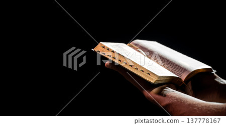 Man's hands hold an open holy Bible in the dark copy space. Man's hands hold an open holy Bible in the dark copy space. 137778167