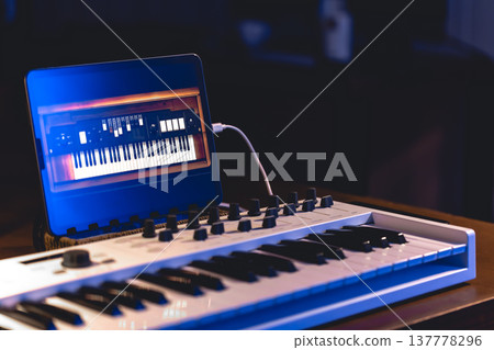 Musical keyboard and tablet in a dark room, music production. Musical keyboard and tablet in a dark room, music production. 137778296