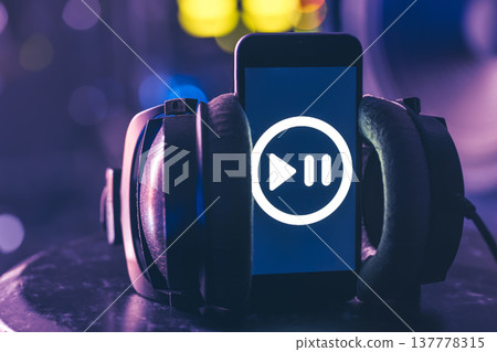 Musical background with a phone and headphones on a dark background. Musical background with a phone and headphones on a dark background. 137778315