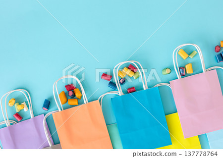 Flat lay, paper bags and chewing gummies on a blue background. 137778764
