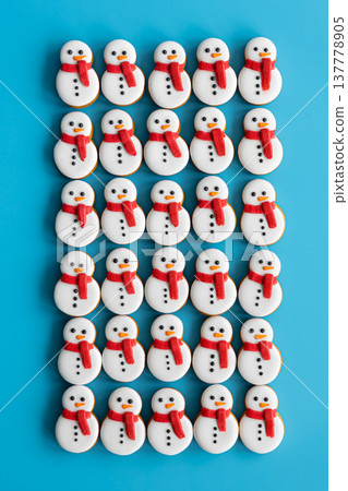 Gingerbread snowmen covered with icing on a blue background, flat lay. Gingerbread snowmen covered with icing on a blue background, flat lay. 137778905