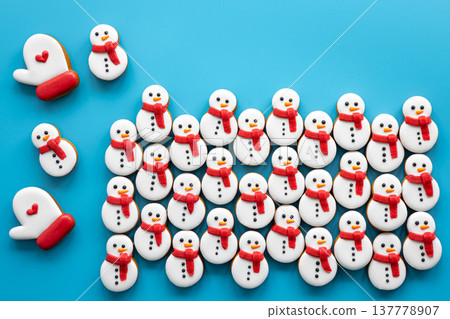 Gingerbread snowmen covered with icing on a blue background, flat lay. Gingerbread snowmen covered with icing on a blue background, flat lay. 137778907