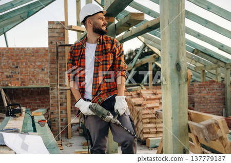Modern electrical drill. Construction worker is on the roof of a house 137779187