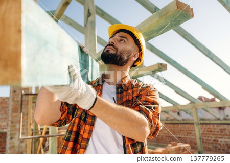 Moving the plank. Construction worker is on the roof of a house 137779265
