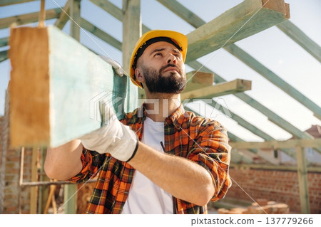 Moving the plank. Construction worker is on the roof of a house 137779266