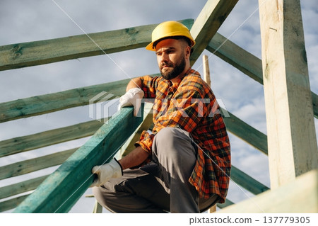 Unfinished place, under sunlight. Construction worker is on the roof of a house Unfinished place, under sunlight. Construction worker is on the roof of a house 137779305
