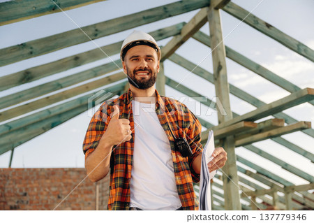 Showing thumb up, smiling. Construction worker is on the roof of a house Showing thumb up, smiling. Construction worker is on the roof of a house 137779346